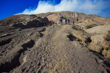 Tourists walking on a plain of volcanic ash and ascending on the Mount Bromo active volcano at...
