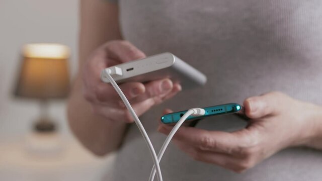 Close-up of a woman holding a Power bank external battery for charging a smartphone.