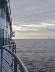 Modern white cruiseship or cruise ship liner at sea cruising the Mediterranean with Liparic Islands...