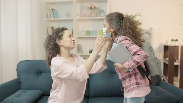 Responsible mom putting protective face mask on daughter before school, health