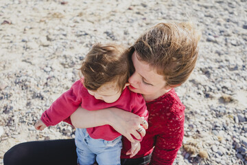 Happy family moment of a young mom enjoying a day on the beach with her baby