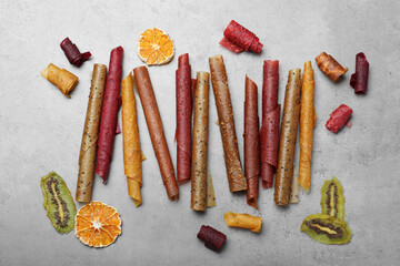 Delicious fruit leather rolls on grey table, flat lay