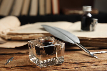 Feather pen and inkwell on wooden table