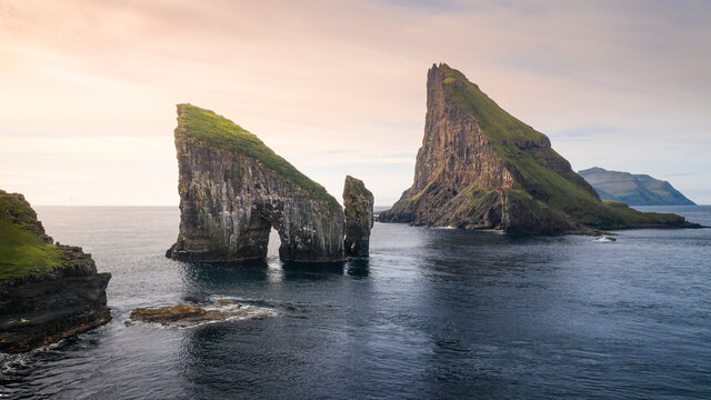 Drangarnier rock formations and Tindholmur island in sunset with clouds on Vagar, Faroe Islands.