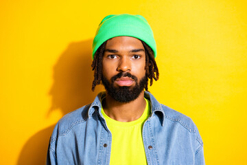 Photo of young handsome attractive calm peaceful afro man in green beanie and jeans jacket isolated on yellow color background