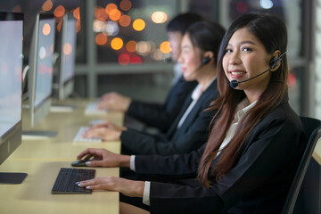 Cute good looking Asian woman officer wearing headphone headset and working with happy face in call...