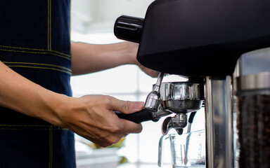 Close up hand Put warm water in a glass. Making a cup of coffee in a coffee machine, the steam and the cup. Espresso maker machine with portafilter close up. Concept Coffee maker in cafe.