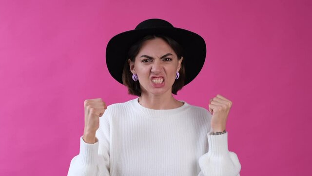 Woman in casual white sweater and hat on pink background isolated angry look to camera saying words    