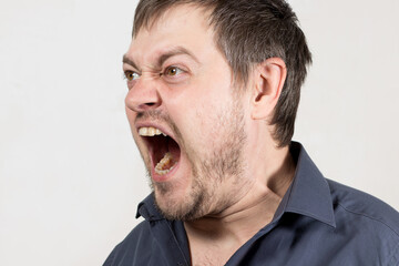 Fototapeta premium An angry aggressive man screams with mouth open. A human cry at a child or a quarrel in the family. Anger and negative emotion with scream.