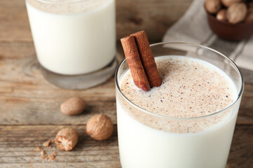 Milk with nutmegs and cinnamon on wooden table, closeup. Space for text