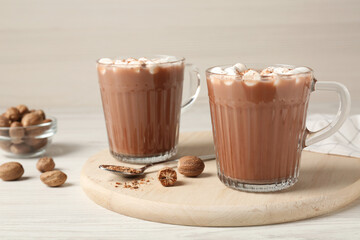 Cocoa drink with nutmegs and marshmallows on white wooden table
