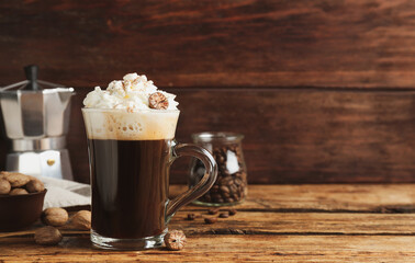Coffee drink with nutmegs and whipped cream on wooden table. Space for text