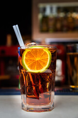 Red alcoholic cocktail with a slice of lime on the bar counter. Close-up, selective focus