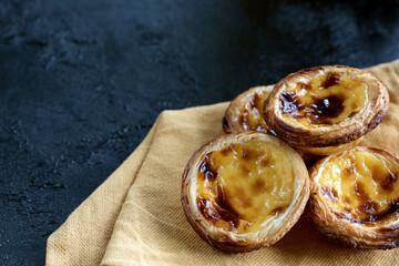 Traditional Portuguese egg tart dessert on dark background