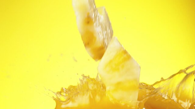 Super slow motion of pineapple slices falling into juice. Filmed on high speed cinema camera, 1000 fps.