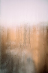  Vertical background texture of a wet window in drops with sun after rain. Warm photo