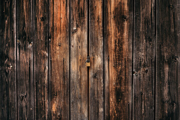 Textured wooden background dark brown fence with a lock.
