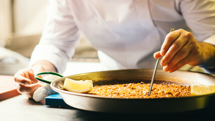 Cooking paella chef checks readiness with tweezers - Spanish food