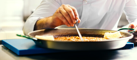 Fototapeta na wymiar Cooking paella chef checks readiness with tweezers - Spanish food