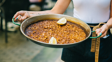 a waiter holding a paella with seafood close-up