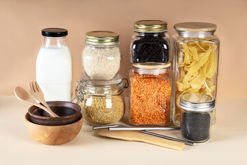 Assortment of uncooked grains, cereals and pasta in glass jars on wooden table. Zero waste concept. Glass jars and bamboo dishes. Sustainable and recyclable.