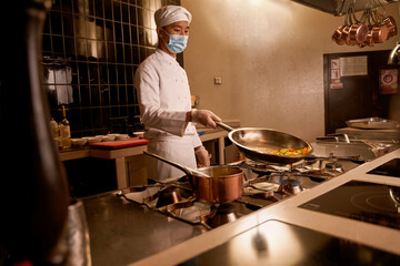 Asian cook tilting a hot pan with vegetable slices