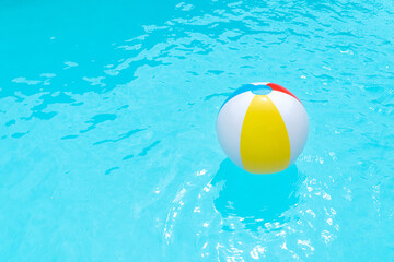 Beach Ball Floating on water surface of a swimming pool. Summer background. Copy space