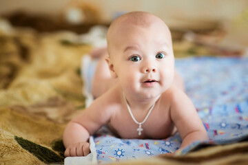 A newborn baby is resting in bed. Children's room. The naked baby is lying on his stomach. Family morning at home. image with selective focus