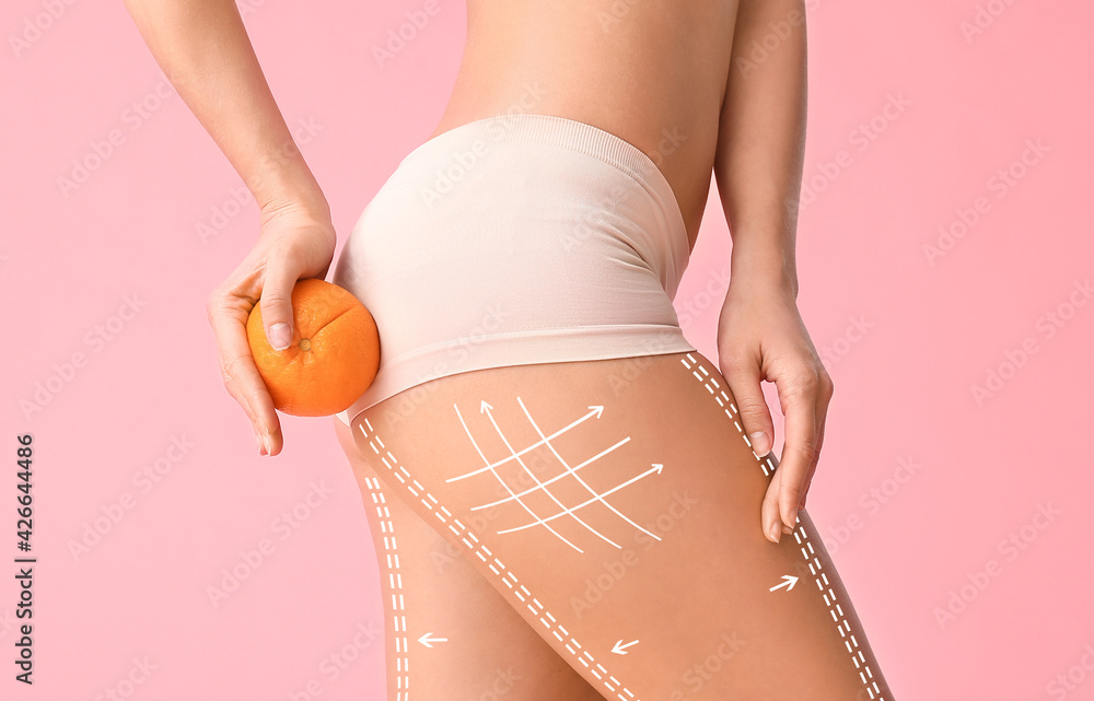 Wall mural young woman with orange fruit on color background. concept of cellulite