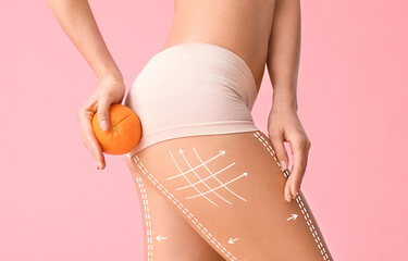 Young woman with orange fruit on color background. Concept of cellulite - obrazy, fototapety, plakaty