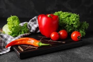 Cutting board with vegetables on dark background