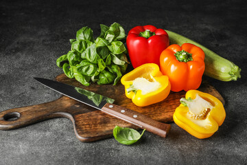 Cutting board with vegetables and knife on dark background
