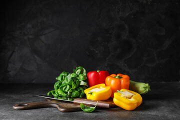 Cutting board with vegetables and knife on dark background