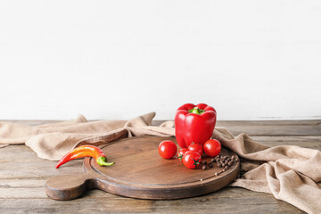 Cutting board with bell pepper and tomatoes on wooden table against white background