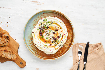 Feta with herbs, spicy honey and mini baguette on a plate on a rustic background. Vegetarian menu,...