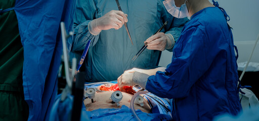 The doctor uses a variety of medical instruments to perform the minimally invasive surgery. Close-up shot of blood-stained hands in sterile gloves and blue uniform.