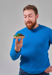 young man with a sandwich with wild black beluga caviar on a light uniform background