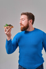 young man with a sandwich with wild black beluga caviar on a light uniform background