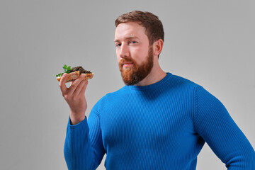 young man with a sandwich with wild black beluga caviar on a light uniform background