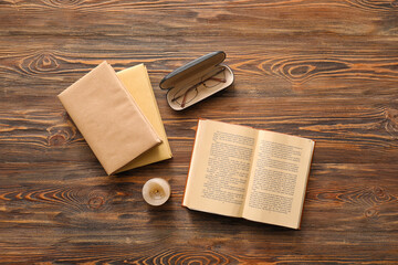 Old books with candle and eyeglasses on wooden background