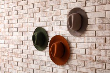 Stylish hats on light brick background
