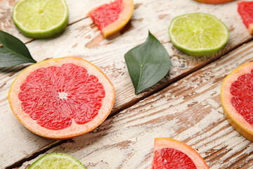 Fresh sliced grapefruit and lime on light wooden background