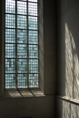 Church stained-glass window with sunlight shining through. The incoming light shines on the wall next to the window