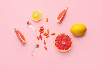 Bottles with vitamin C, pills and citrus fruits on color background