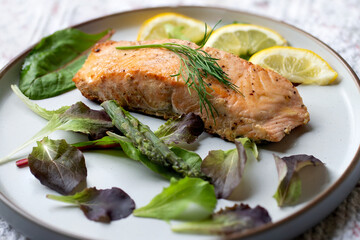 Pan fried salmon fillet with dill,lemon slices and some salad leaves