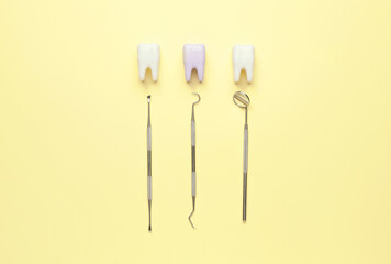 Dentist's tools and plastic teeth on color background