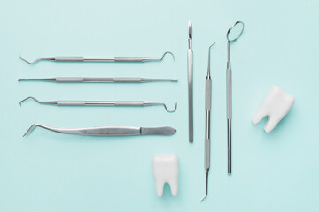 Dentist's tools and plastic teeth on color background