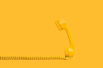 Tubo de teléfono antiguo con cable de color amarillo sobre un fondo amarillo liso y aislado. Vista...