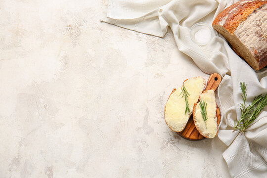 Slices of fresh bread with butter and rosemary on light background