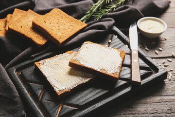 Slices of fresh bread with butter and sunflower seeds on wooden background, closeup